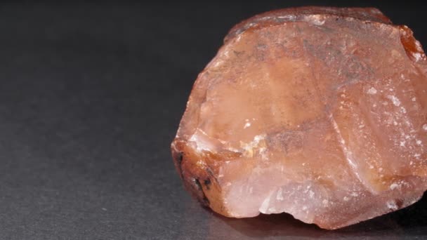 Mineraal is een carneool op een zwarte achtergrond. Een close-up steen nugget. — Stockvideo
