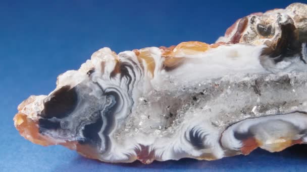 Der Achat in Nahaufnahme auf blauem Hintergrund. Eine Scheibe Mineral. Makrovideo von Chalcedon, Quarz. — Stockvideo