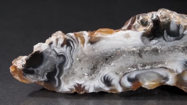 A ágata close-up em um fundo preto. Uma fatia de mineral. Calcedônia, quartzo em macro vídeo. close-up — Vídeo de Stock