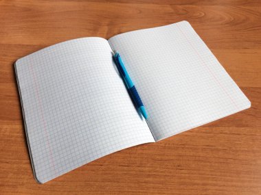 Defter, ahşap bir masa üzerinde kalem.