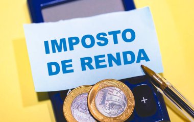 Brezilya gerçek sikkeleri, kalem, hesap makinesi ve IMPOSTO DE RENDA metni ile not