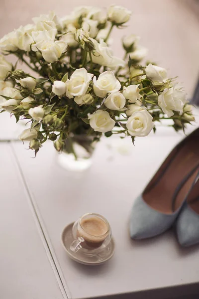 Bride\'s  shoes and bouquet stand on the windowsill