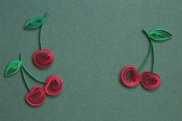 Beautiful Ripe cherries designs isolated on green paper background. Paper quilling of cherry - fresh fruit, natural berry. Berries with stems and green leaves. Hand made of paper quilling technique.