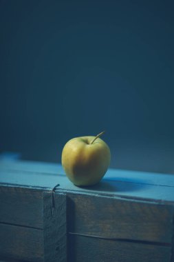 Mavi arka planda yeşil elma resmi. Tahta kutuda lezzetli yeşil elma. Eski. 