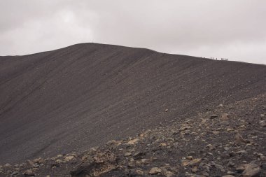 Tepesinde insanlar olan Hverfell Caldera volkanı. Hverfjall, İzlanda simgesi. Bir grup dağcı volkanın tepesinden aşağı iniyor. Dağcılık tırmanma grubu. 