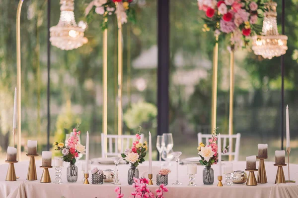 Zarif çiçek süslemesi, güneşli bir öğleden sonra güneşli bir bahçede romantik bir düğün masası kurulmasını sağlar.