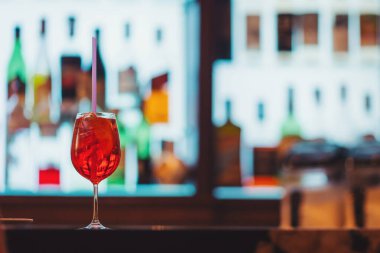 Çekici bir kokteyl canlı bir gece boyunca canlı bir arkaplanda duran renkli şişelere karşı bir bar tezgahında dinleniyor.