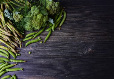 Yeşil organik vejetaryen ürünlerin koyu ahşap arka plan kompozisyon: bezelye, dereotu, brokoli, kuşkonmaz. Üst te. Çerçeve Taze Yeşil gıda, ahşap tahta üzerinde Yeşil sebze