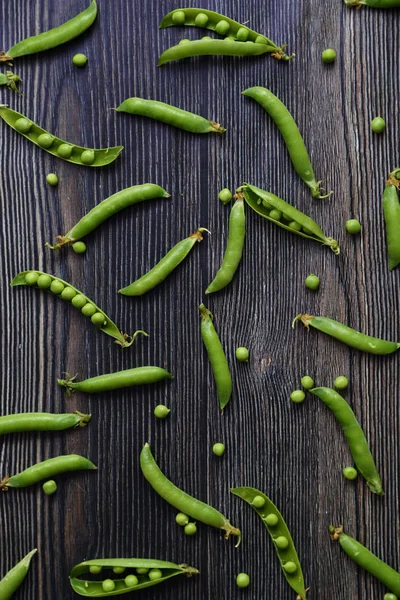 Vertical Peas in pods pattern. Top view of fresh vegetable on a dark wooden background green pea pod with beans isolated. Horizontal composition isolated on a old rustic wooden surface