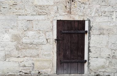 Krem ve beyaz eski tuğla kireçtaşı doku arka plan ev duvarı eski koyu ahşap kapı ile. Sol köşede metin için yer ile arka düz taş granit yüzey arka plan grunge desen.