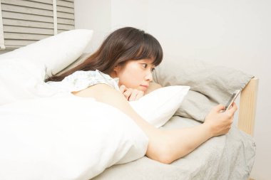 Genç kadın uyumadan önce cep telefonu kullanıyor.