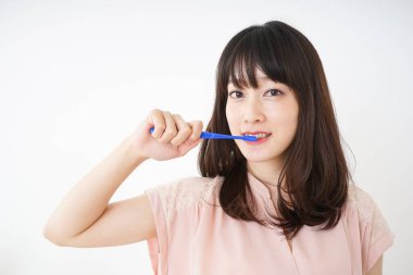  Genç bir kadın dişlerini fırçalıyor.