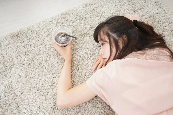 Junge Asiatin Liegt Mit Getränk Auf Teppich — Stockfoto