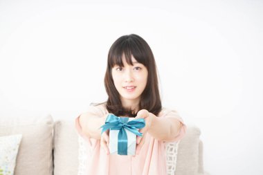 Genç Asyalı kadın küçük bir hediye kutusu tutuyor.