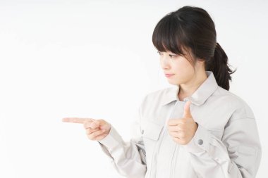 Genç Asyalı kadın parmağıyla işaret ediyor ve başparmağını kaldırıyor.