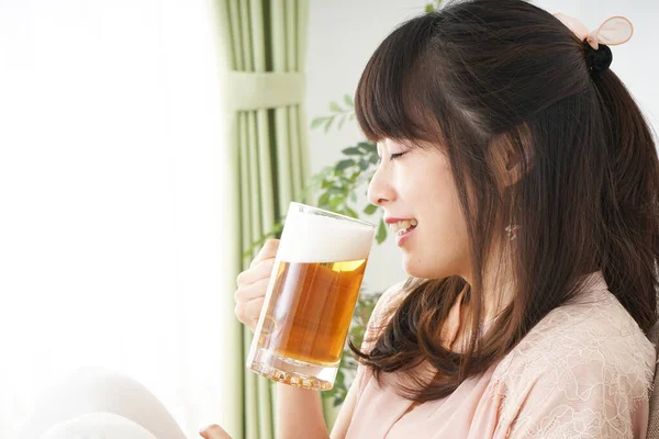 在家里喝啤酒的年轻女性 在家里喝啤酒的年轻女性 — 图库照片