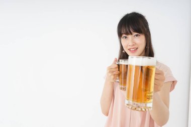 Genç Asyalı kadın evde bira içiyor.