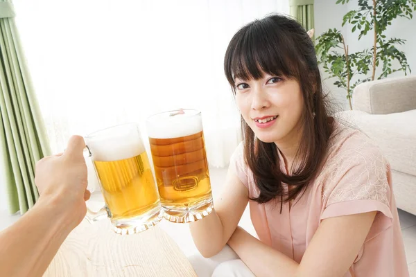 年轻的亚洲女人在家里喝啤酒 — 图库照片