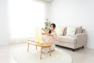 Genç Asyalı kadın elbiselerini katlıyor.