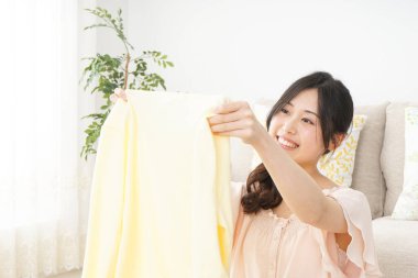 Genç Asyalı kadın elbiselerini katlıyor.