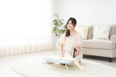 Genç Asyalı kadın ütü yapıyor.