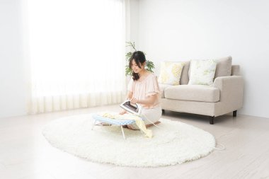 Genç Asyalı kadın ütü yapıyor.