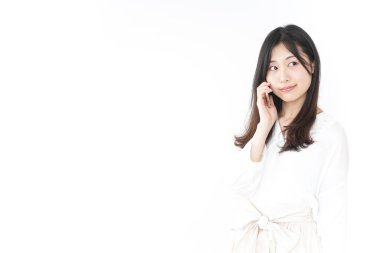 Genç Asyalı kadın telefonda konuşuyor.