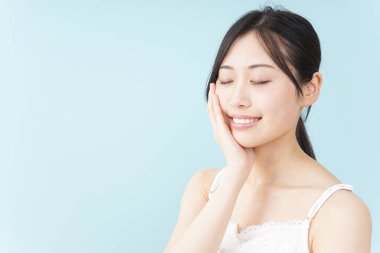 Genç Asyalı kadın elleriyle yüzüne dokunuyor, cilt konsepti