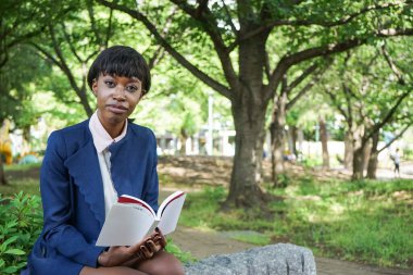 Parkta kitap okuyan Afrikalı kadın.