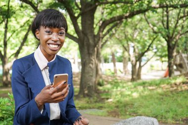 Dışarıda yürürken akıllı telefon kullanan Afrikalı bir kadın.