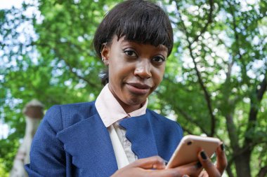 Dışarıda yürürken akıllı telefon kullanan Afrikalı bir kadın.