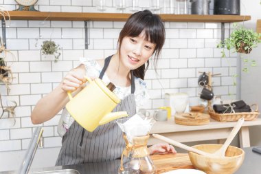 Genç Asyalı kadın damlatan kahve yapıyor.