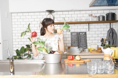 Genç Asyalı kadın organik sebze pişiriyor  