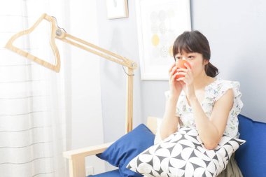 Asyalı genç bir kadın evde tek başına vakit geçiriyor.