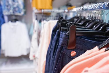 Alışveriş merkezinde asılı kıyafetlerin yakın çekimi.