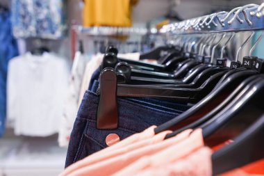 Alışveriş merkezinde asılı kıyafetlerin yakın çekimi.