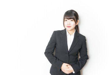 Takım elbiseli genç Asyalı kadın beyaz üzerinde yalnız poz veriyor.