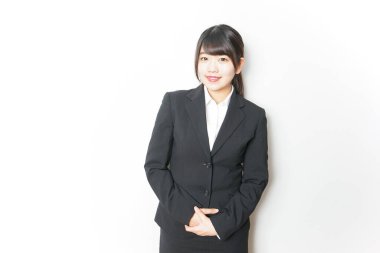 Takım elbiseli genç Asyalı kadın beyaz üzerinde yalnız poz veriyor.