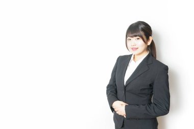 Takım elbiseli genç Asyalı kadın beyaz üzerinde yalnız poz veriyor.