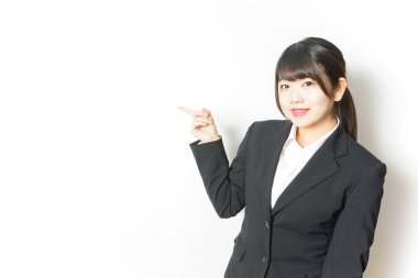 Takım elbiseli genç Asyalı kadın, parmak göstererek beyazı işaret ediyor.