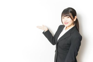 Takım elbiseli genç Asyalı kadın beyaz üzerinde yalnız poz veriyor.