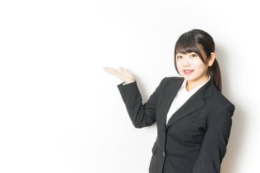 Takım elbiseli genç Asyalı kadın beyaz üzerinde yalnız poz veriyor.