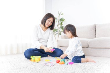 Anne ve çocuk halının üstünde oyuncaklarla oynuyor.