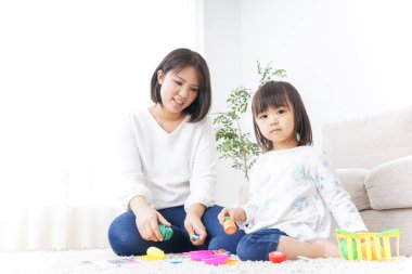 Anne ve çocuk halının üstünde oyuncaklarla oynuyor.