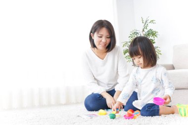 Anne ve çocuk halının üstünde oyuncaklarla oynuyor.
