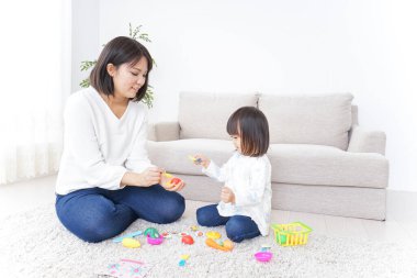 Anne ve çocuk halının üstünde oyuncaklarla oynuyor.