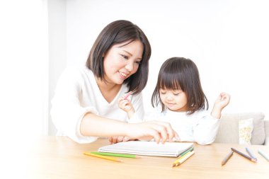 Anne ve çocuk evde birlikte çizim yapıyorlar.