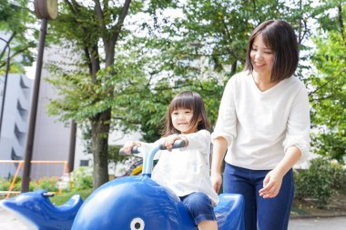 Anne ve çocuk parkta birlikte oynuyorlar.