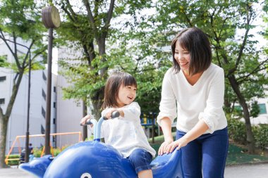 Anne ve çocuk parkta birlikte oynuyorlar.