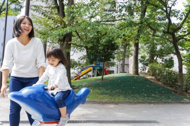 Anne ve çocuk parkta birlikte oynuyorlar.